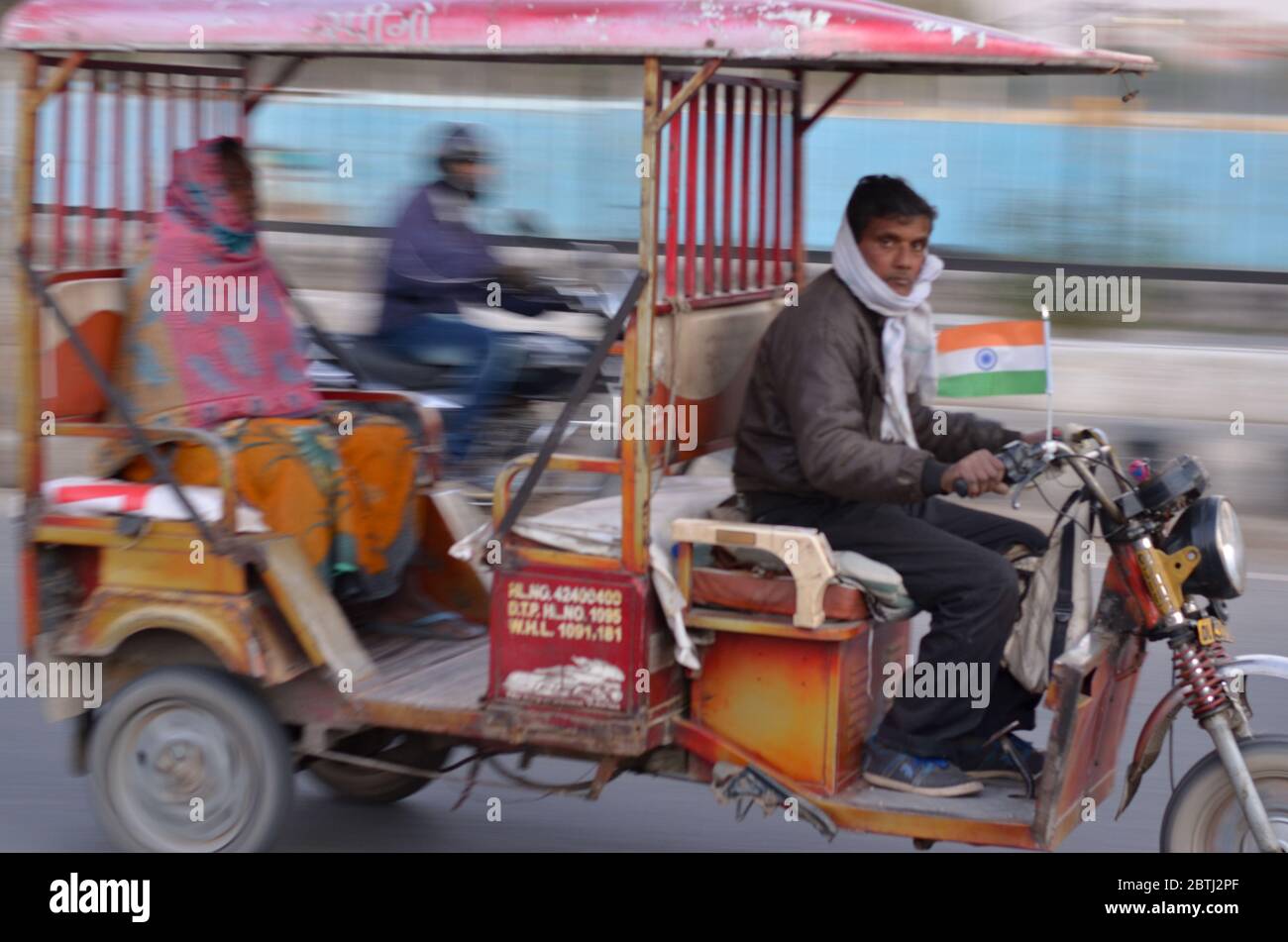 Delhi, India, 2020.Panning colpo di un e-rickshaw veloce sulle strade di Delhi. I risciò elettrici sono modalità economica di trasporto in India per ultimo m Foto Stock