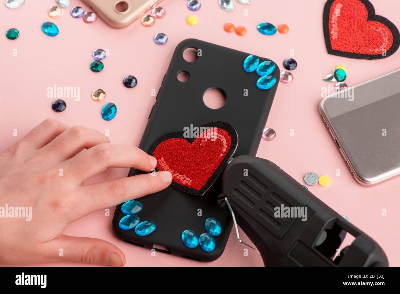 Ragazza che fissa la patch cuore rosso sulla custodia nera del telefono Foto Stock