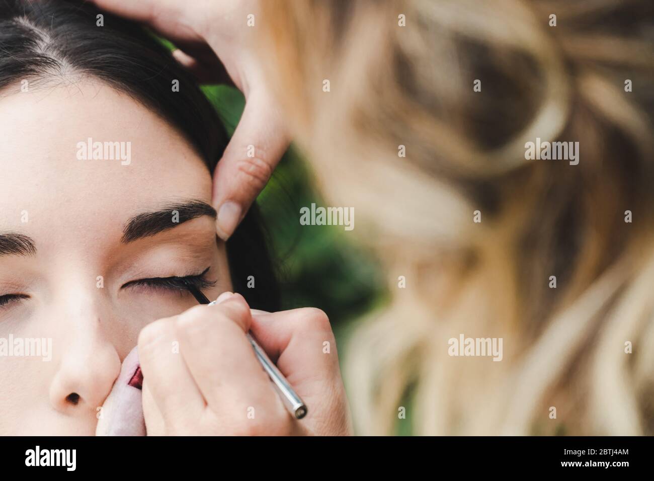 Un artista del trucco sta disegnando la linea dell'occhio ad un modello. Si tratta di un'immagine ravvicinata. Foto Stock