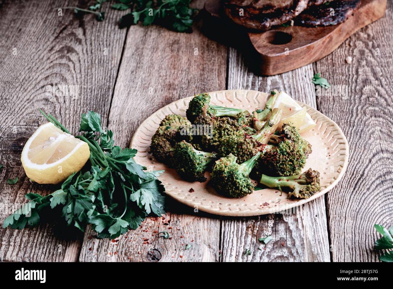 Broccolini biologici cotti, erbe e limone su tavola rustica in legno, sano pasto a base di piante Foto Stock