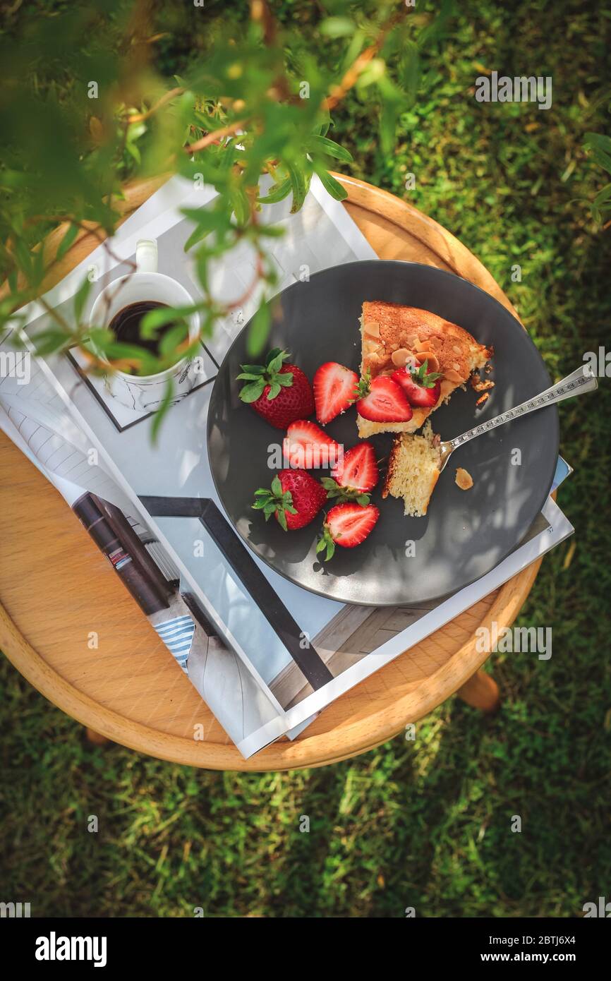 Torta fatta in casa con fragole servite sotto un albero in giardino Foto Stock