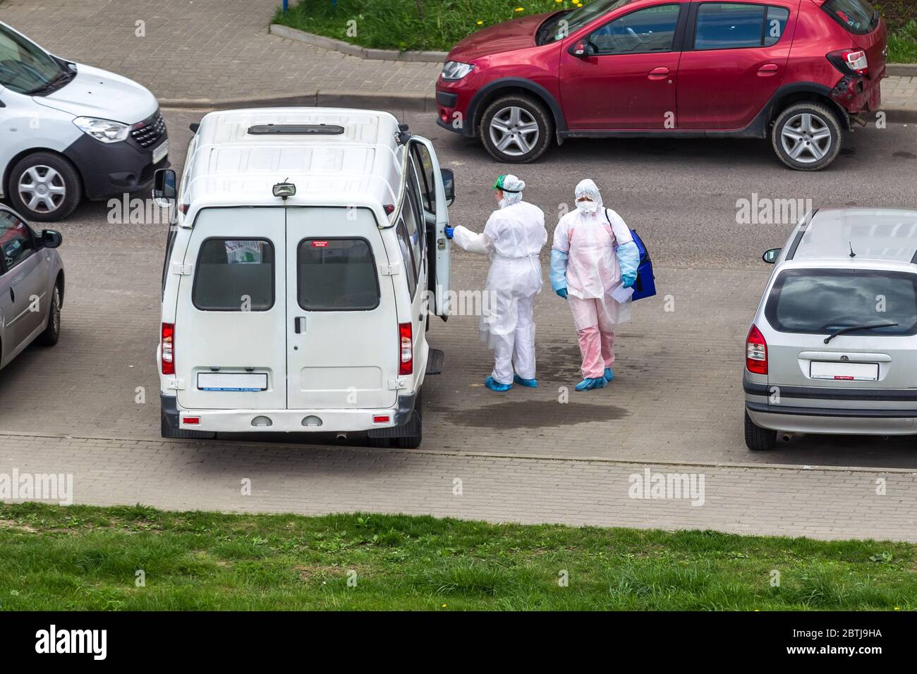 Il medico indossa indumenti protettivi bianchi, . Epidemia di infezione da coronavirus. Virologo in visita al paziente in auto-isolamento. Foto Stock