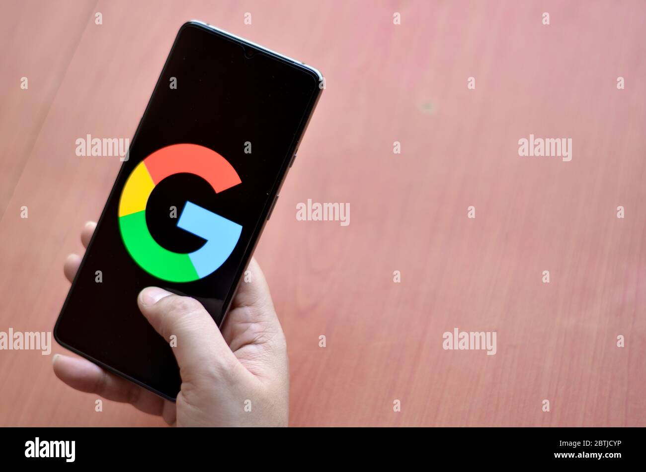 California, Stati Uniti, 2020. Logo Google su uno schermo mobile contro uno sfondo di legno tenuto da una donna. Foto Stock