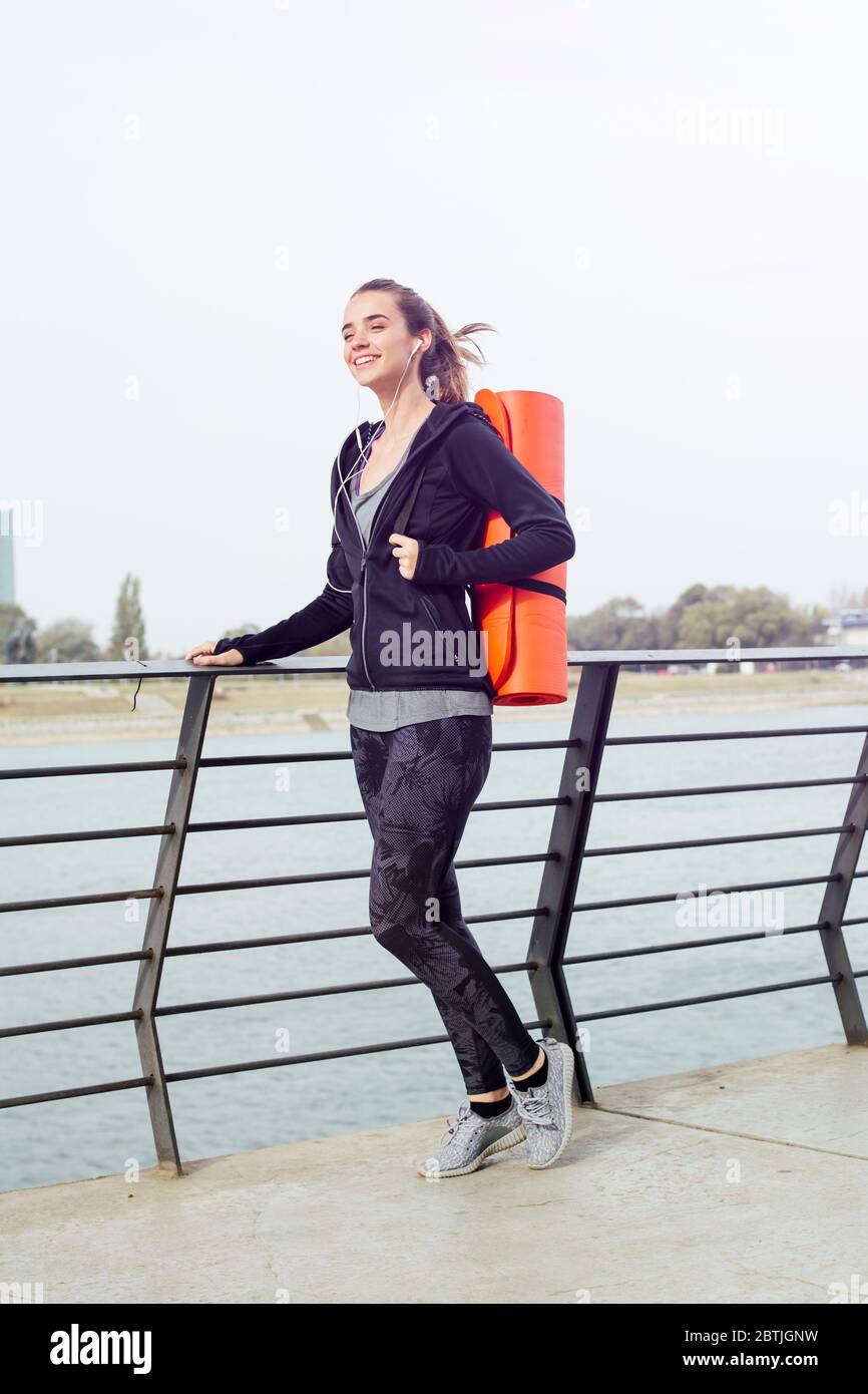 Giovane donna sportiva in vestibilità sportiva con tappeto in gomma laminato per yoga pilates all'aperto Foto Stock