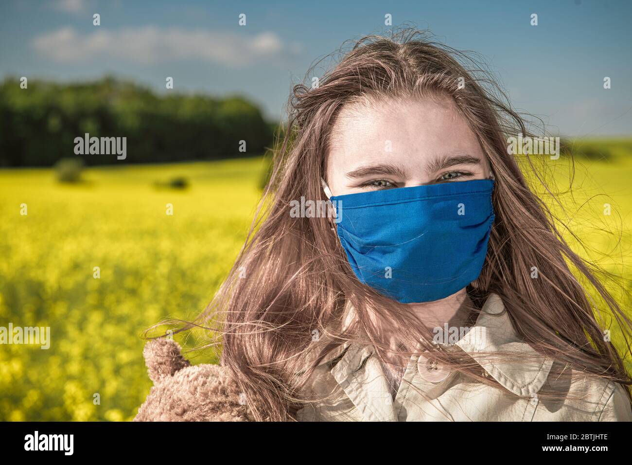 Felice ragazza caucasica teenager con coperta da maschera faccia combattere focolaio di virus. Paesaggio pittoresco paesaggio di campagna estiva. Foto Stock