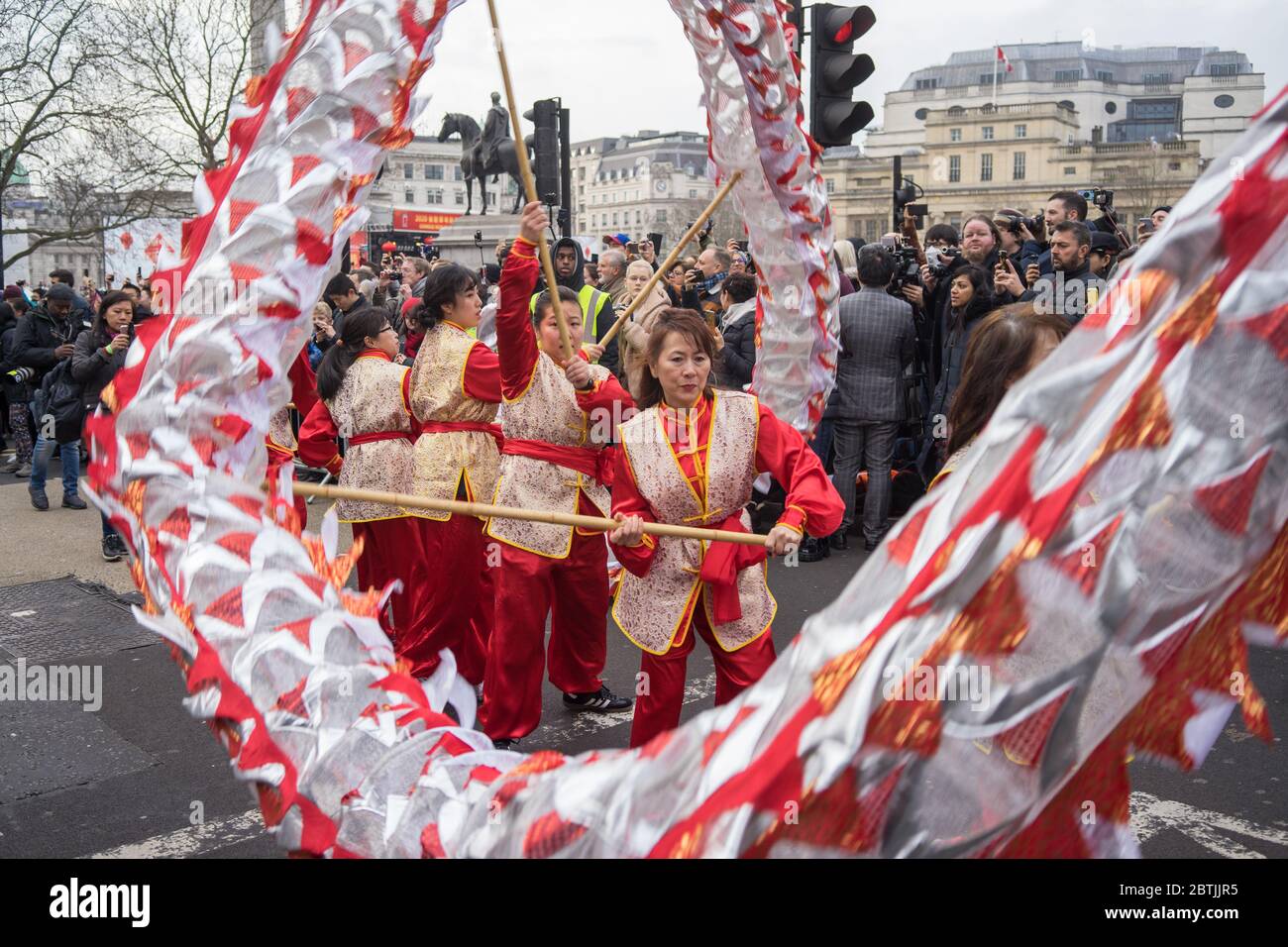 Signora in costume rosso che sventola parte di un drago. Focus su signora. Festa di Capodanno cinese Parata. Londra Foto Stock
