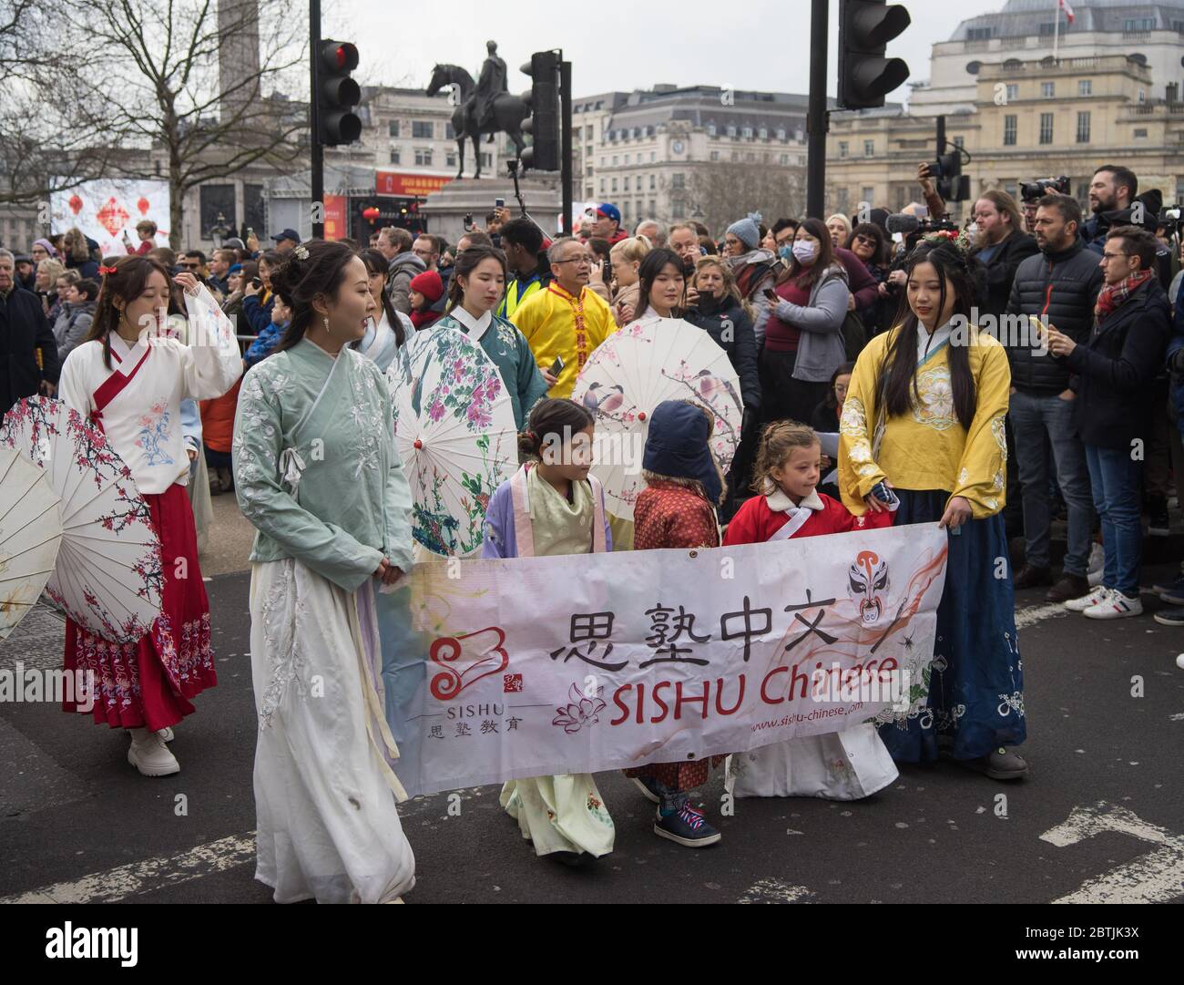 Donne e bambini in abito tradizionale con un banner cinese Sishu. Festa di Capodanno cinese Parata. Londra Foto Stock