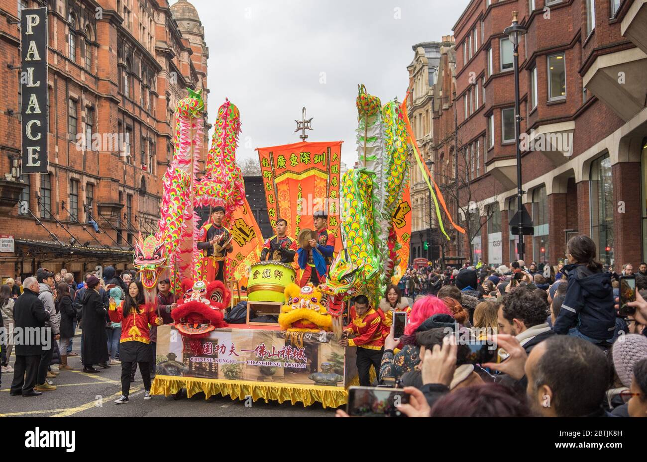 Grande galleggiamento di percussionisti che scendono lungo una strada piena di persone che guardano e scattano foto. Festa di Capodanno cinese Parata. Londra Foto Stock