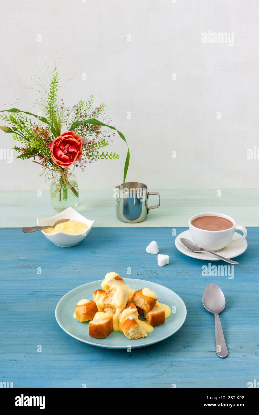 Panini con zabaglione o crema alla vaniglia, o eggnog, gustoso dessert o portata principale. Sfondo di legno blu. Foto Stock