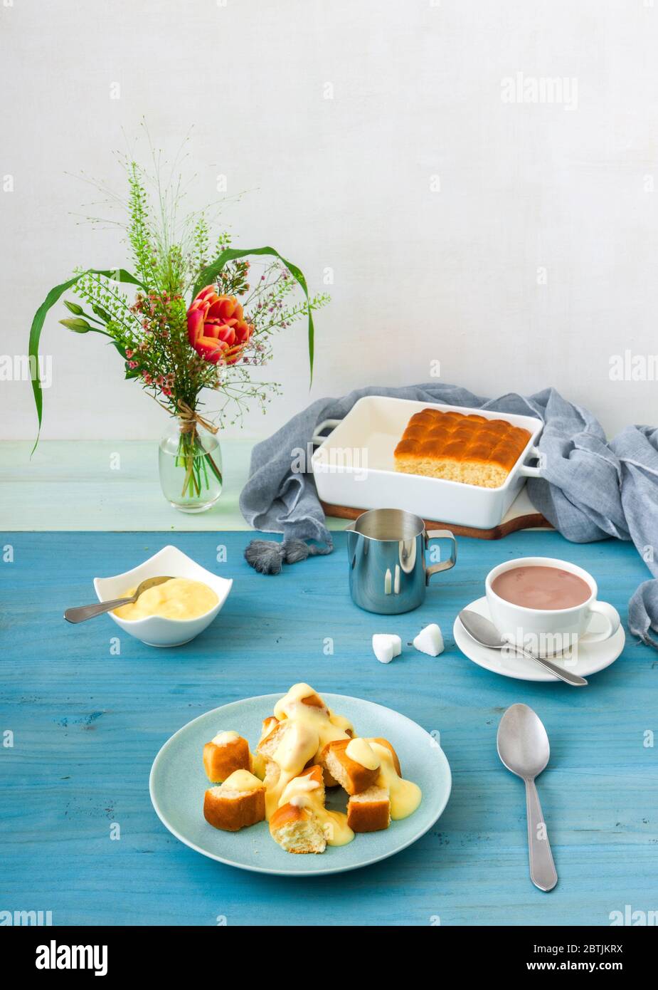 Panini con zabaglione o crema alla vaniglia, o eggnog, gustoso dessert o portata principale. Sfondo di legno blu. Foto Stock