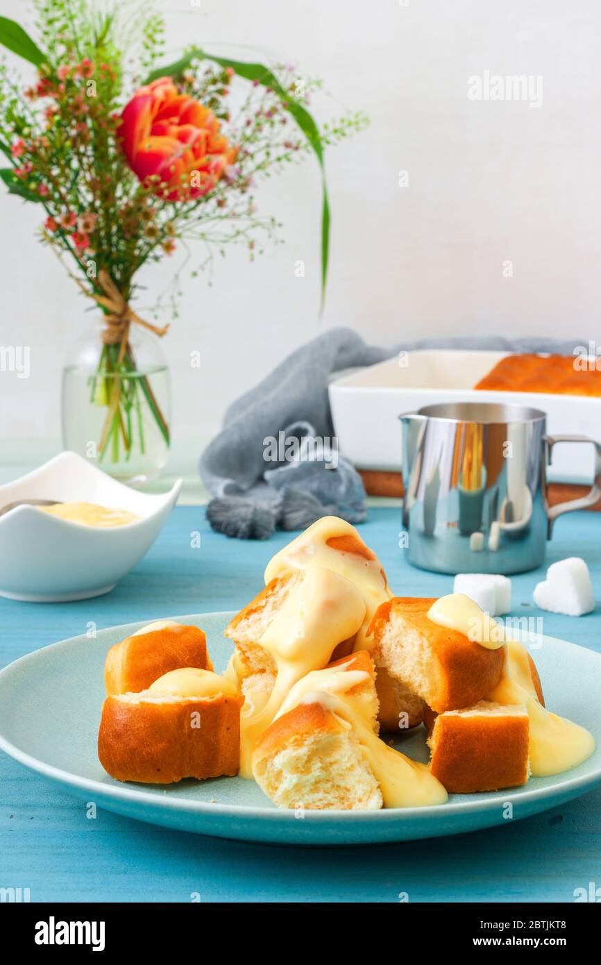 Panini con zabaglione o crema alla vaniglia, o eggnog, gustoso dessert o portata principale. Sfondo di legno blu. Foto Stock