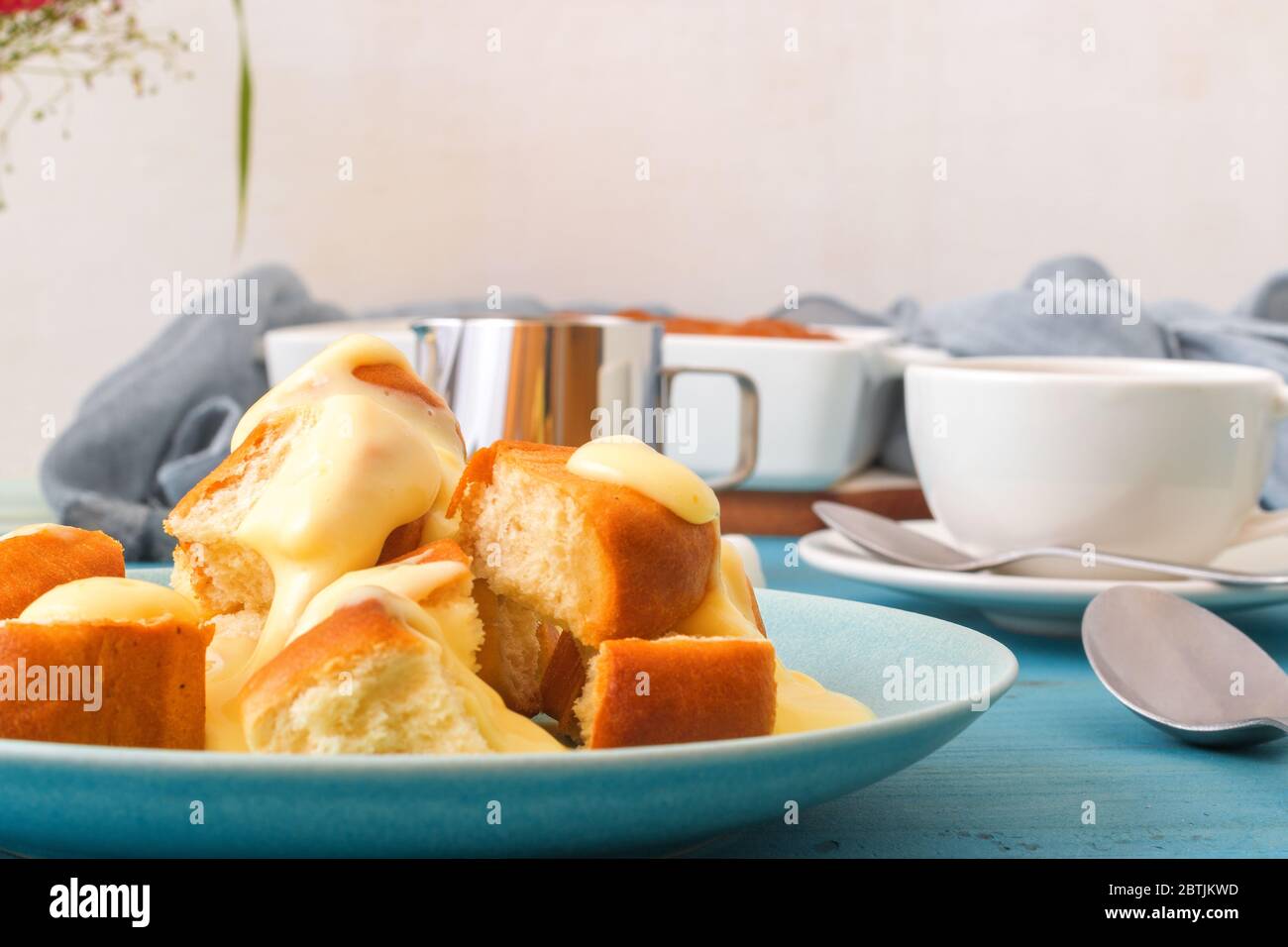 Panini con zabaglione o crema alla vaniglia, o eggnog, gustoso dessert o portata principale. Sfondo di legno blu. Foto Stock