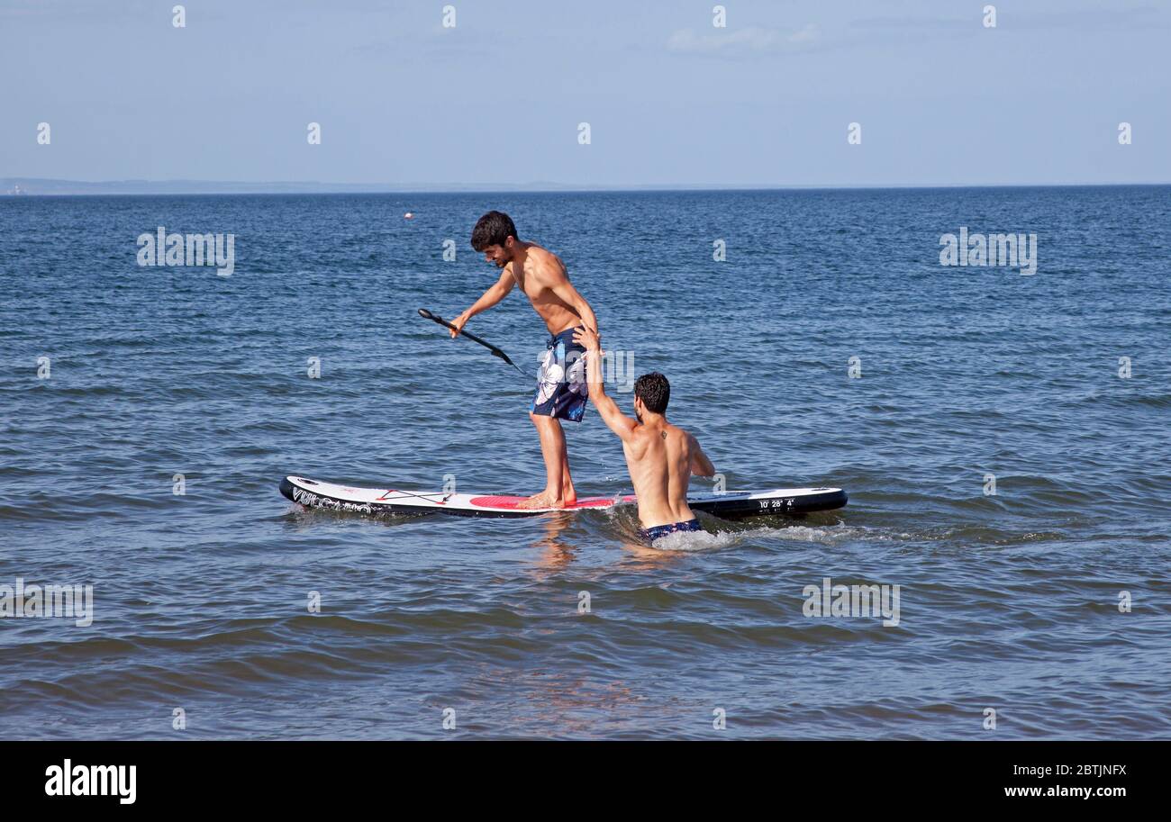 Portobello, Edimburgo, Scozia, Regno Unito. 26 maggio 2020. Atmosfera più rilassata al mare nel tardo pomeriggio, quando la Scozia si avvicina alla fine della fase 1 di Coronavirus Lockdown. Temperatura di 19 gradi e soleggiata. Nella foto dei fratelli Harrison, goditi il paddle boarding. Foto Stock