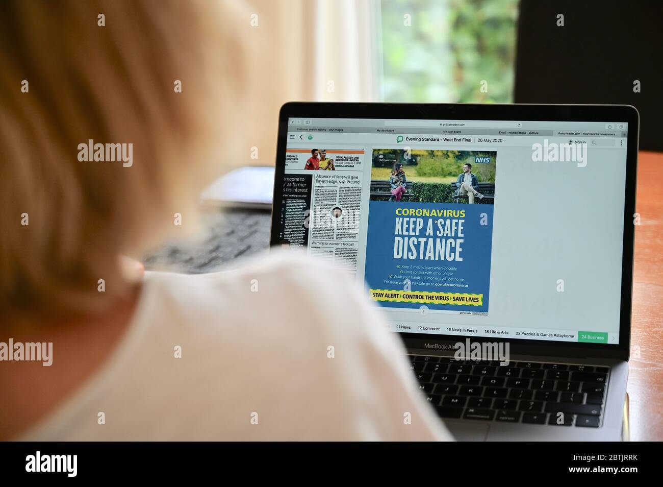 Coronavirus (COVID-19) pandemico. Coronavirus "mantenere una distanza di sicurezza". Una donna vede la guida NHS sul suo laptop. Foto Stock