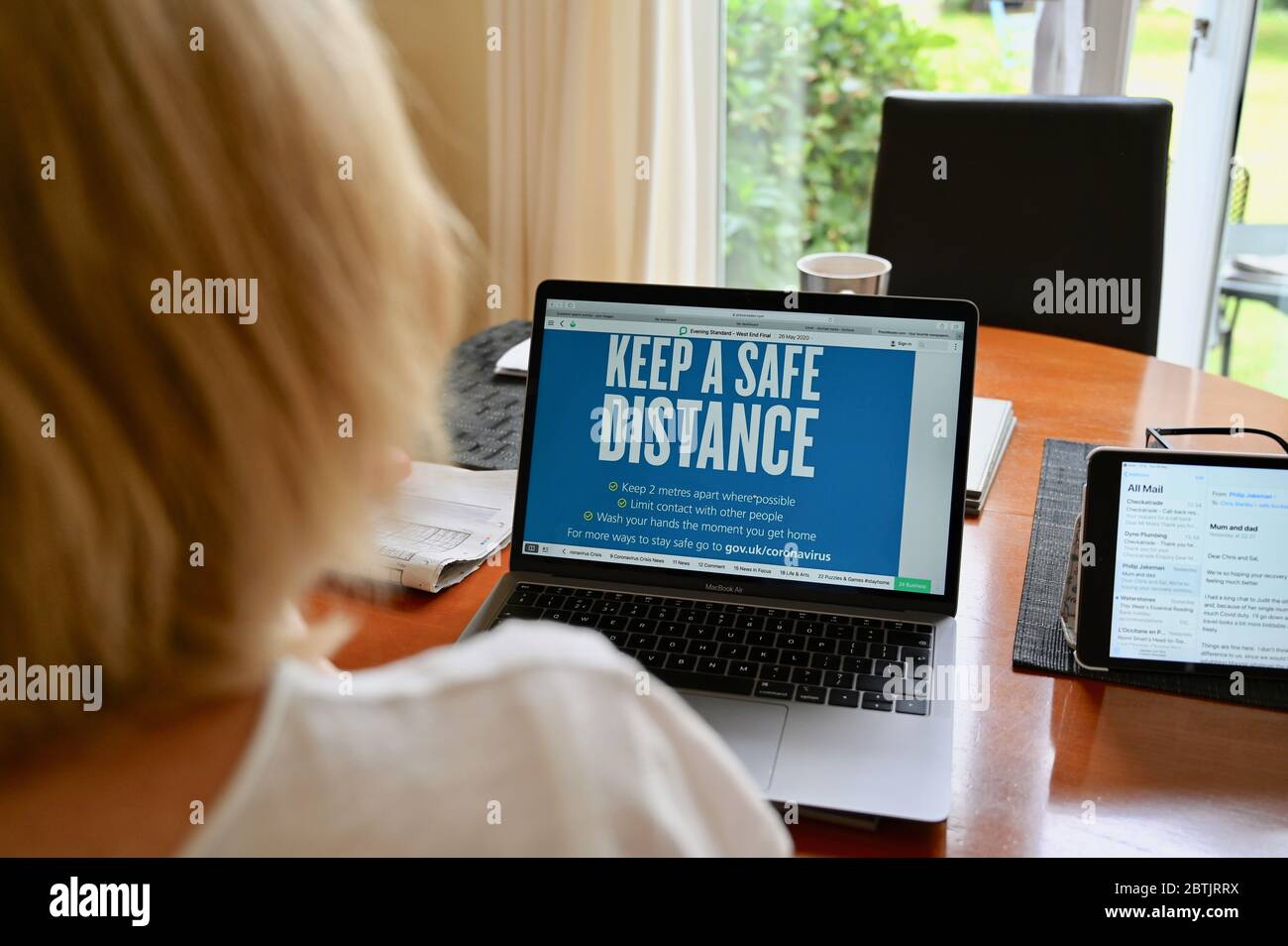 Coronavirus (COVID-19) pandemico. Coronavirus "mantenere una distanza di sicurezza". Una donna vede la guida NHS sul suo laptop. Foto Stock