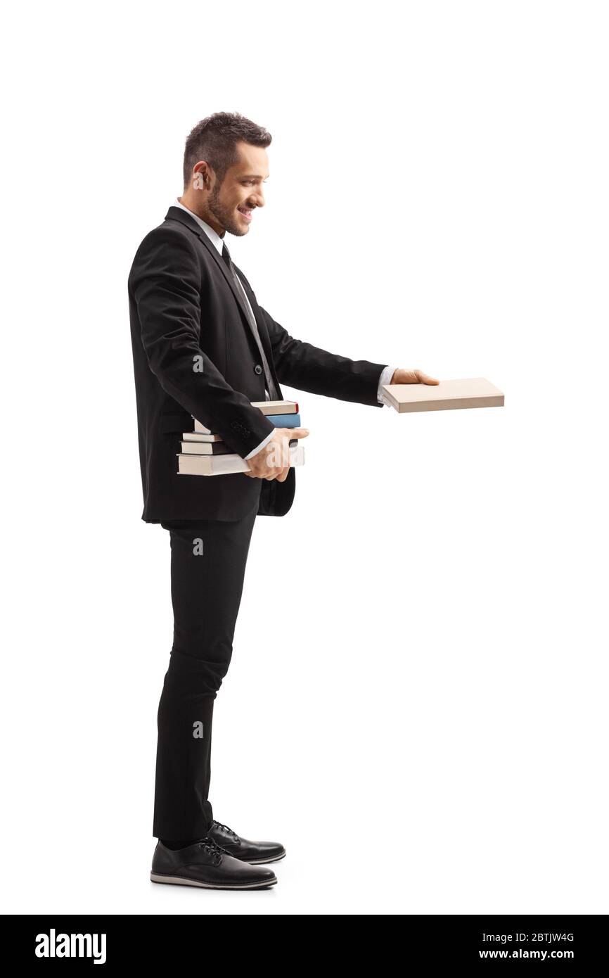 Foto di un uomo in un vestito nero che tiene un mucchio di libri e che dà un libro isolato su sfondo bianco Foto Stock