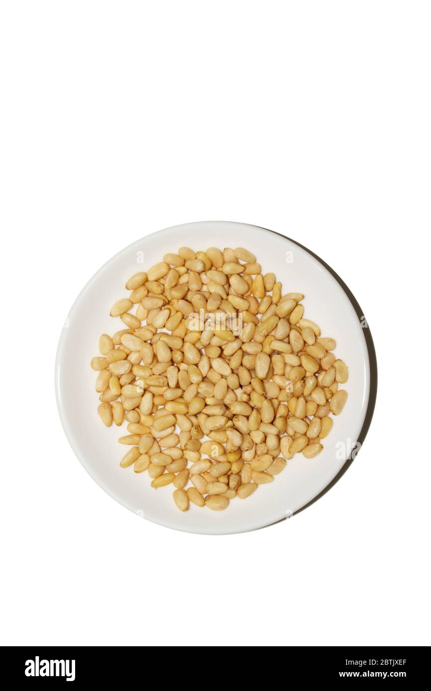 Cibo biologico. Pinoli su sfondo bianco. I dadi di cedro si appiattisco su un piatto bianco. Concetto agricolo. Supercibo, vista dall'alto, spazio per la copia. Banner Foto Stock