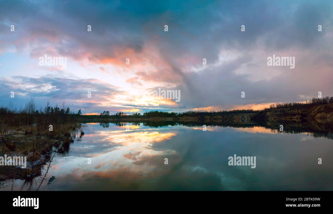Immagine speculare nel lago di ripide rive al tramonto. Vsevolozhsk. Leningrad region.Panorama . Foto Stock