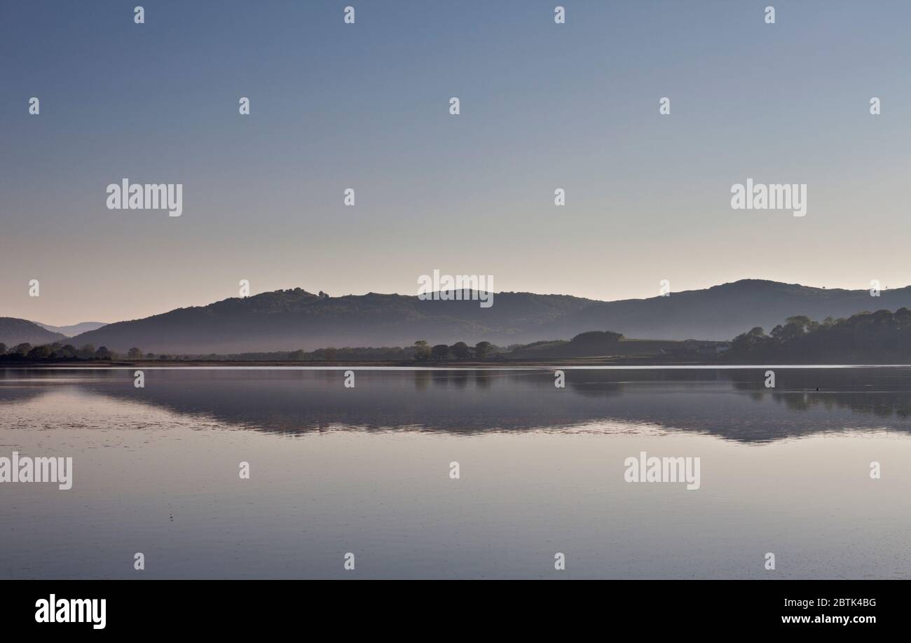 Vista a nord dall'estuario di Levens, Cumbria sud con le colline del distretto del lago riflesse nel fiume Levens Foto Stock