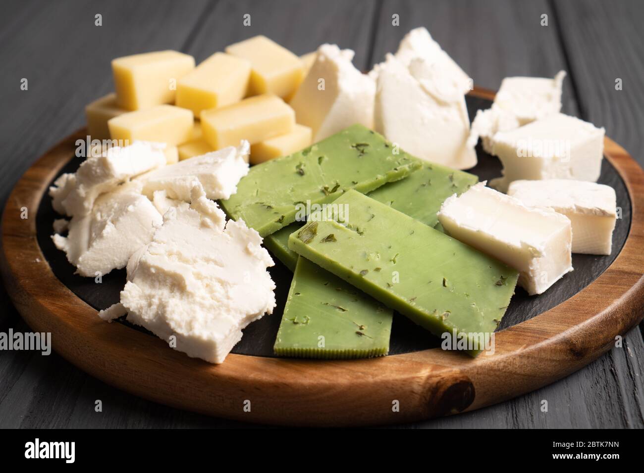 Primo piano sul piatto di formaggio. Formaggi bianchi, gialli e verdi. Cibo sano. Fette di formaggi naturali. Vista laterale. Foto Stock