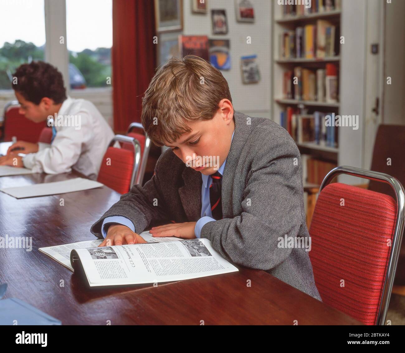 Ragazzo di scuola giovane che studia in biblioteca scolastica, Surrey, Inghilterra, Regno Unito Foto Stock