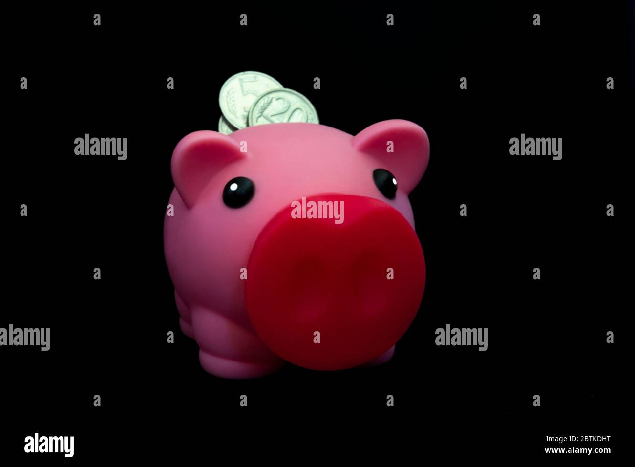 Rosa piggy banca piena di monete su uno sfondo nero. Concetto di dove investire i vostri risparmi. Fare soldi Foto Stock