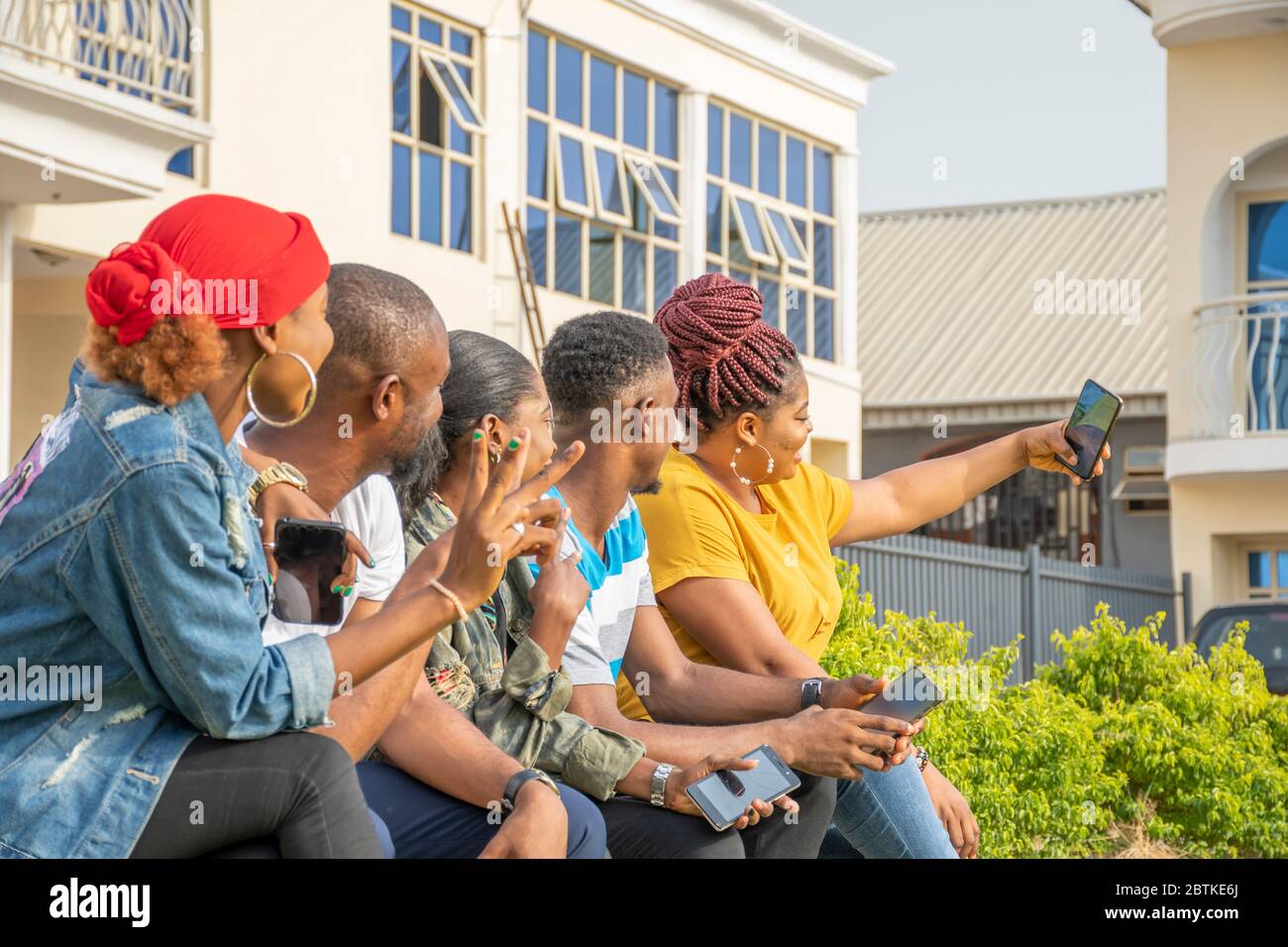 gruppo di giovani amici africani che si accaniscono insieme all'aperto, divertendosi, prendendo un selfie Foto Stock