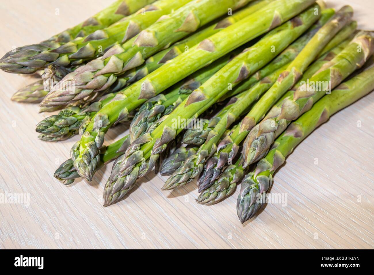 Vista ravvicinata di un fascio di asparagi freschi (Asparagus officinalis) tagliati a denti (punte e lance) su un piano in primavera Foto Stock