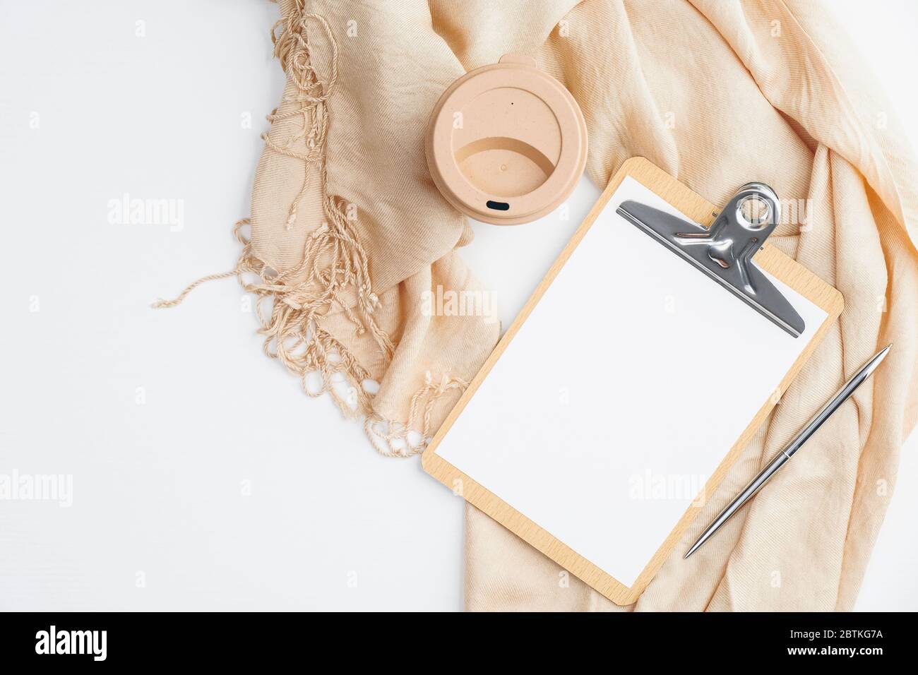 Accogliente scrivania home Office con coperta beige, tazza di caffè, appunti con nota di carta vuota su sfondo bianco. Disposizione piatta, vista dall'alto. Igge o nordic styling Foto Stock