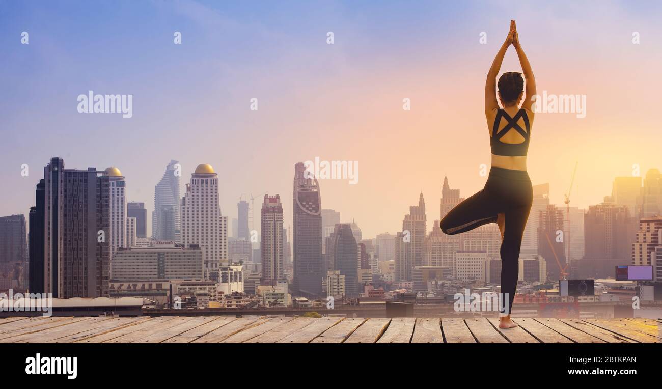 La ragazza sportiva sta facendo yoga su un tramonto. Yoga e meditazione in una città moderna. Foto Stock