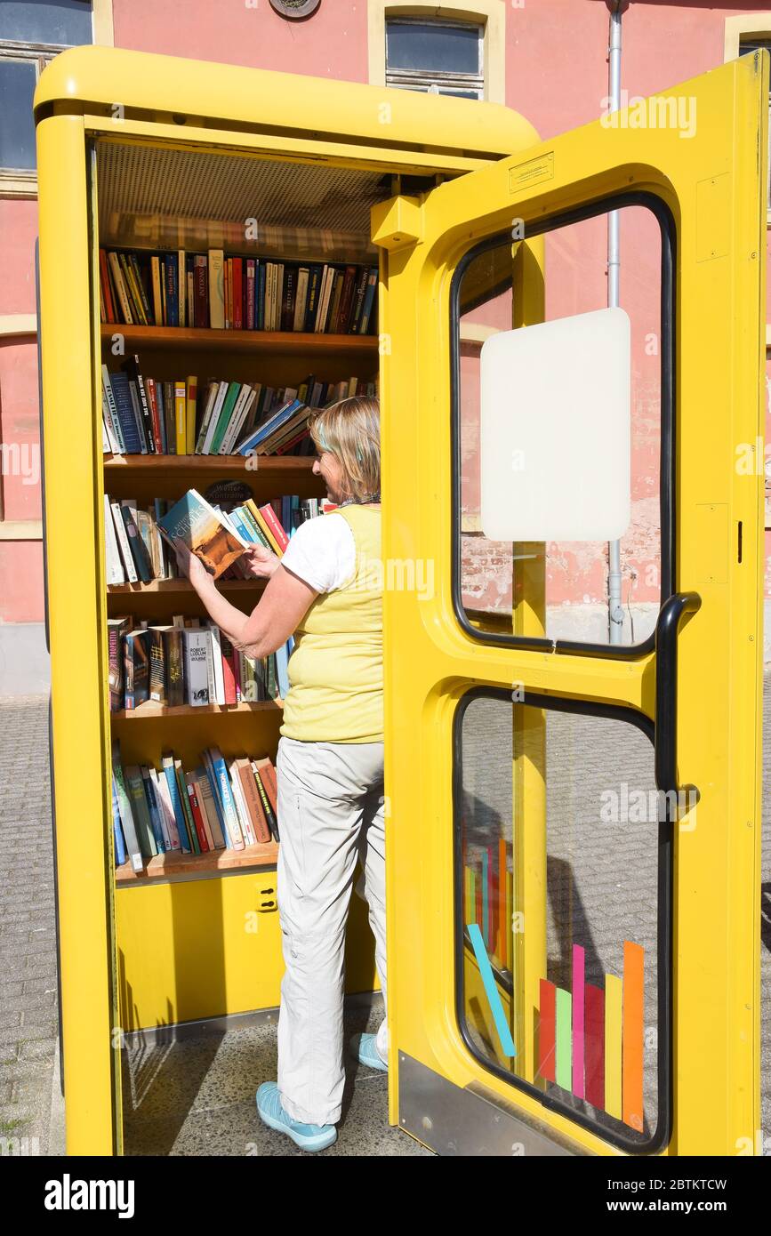 21 maggio 2020, Sassonia-Anhalt, Wörlitz: In una vecchia cabina telefonica, una donna sta in piedi in uno scaffale con libri da portare via gratuitamente. Con l'iscrizione 'Befreite Bücher' (libri liberati) la cabina telefonica in disuso appartiene alla libreria antiquaria 'Chiefes Haus' a Wörlitz. Su un cartello appiclato alla porta, gli interessati sono accolti e invitati a mettere i libri dritti. I libri portati con sé possono essere ordinati o consegnati presso la libreria antiquaria. Foto: Waltraud Grunitzsch/dpa-Zentralbild/ZB Foto Stock