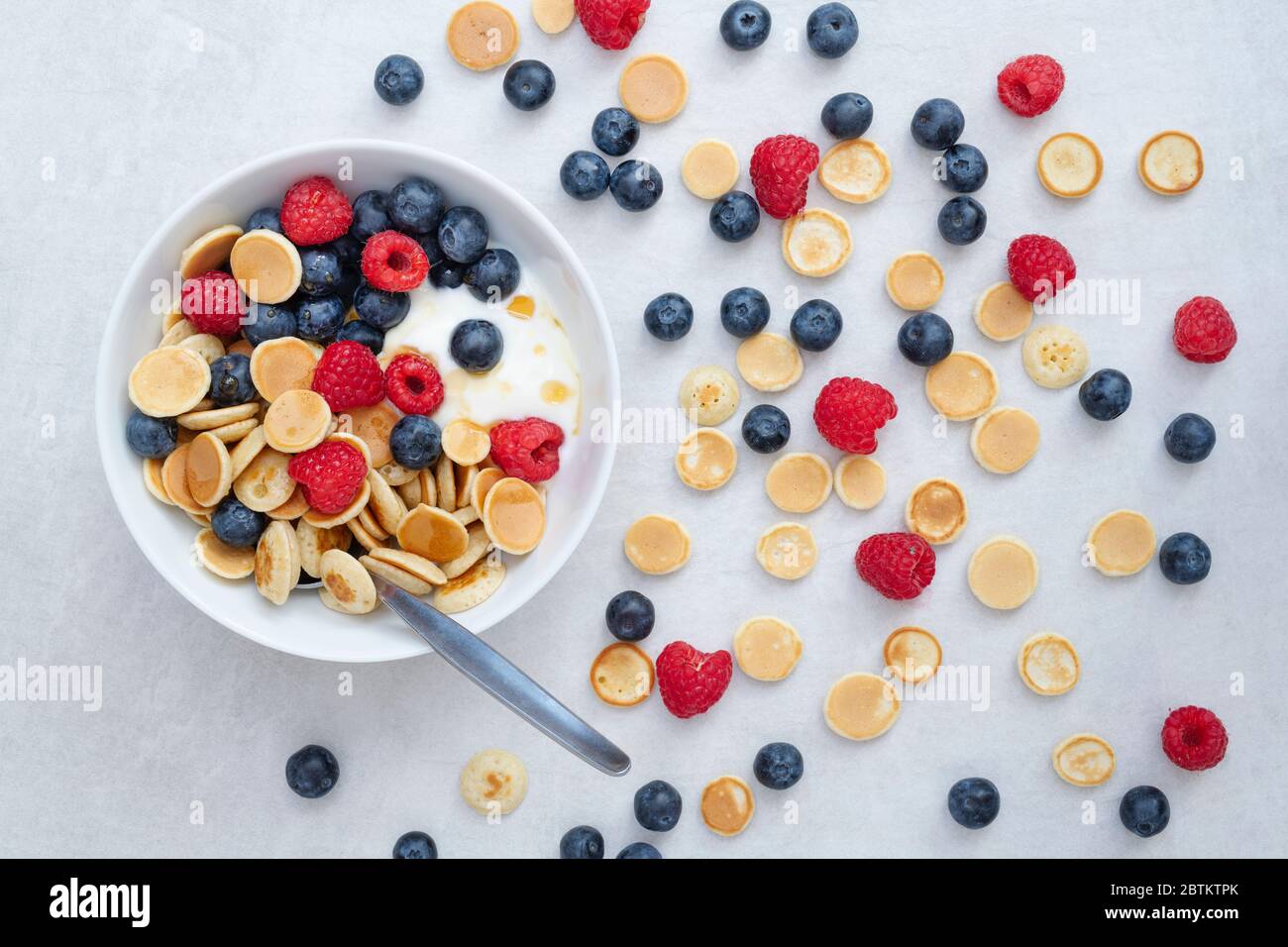Ciotola di frittelle di cereali con mirtilli lamponi yogurt e sciroppo d'acero Foto Stock
