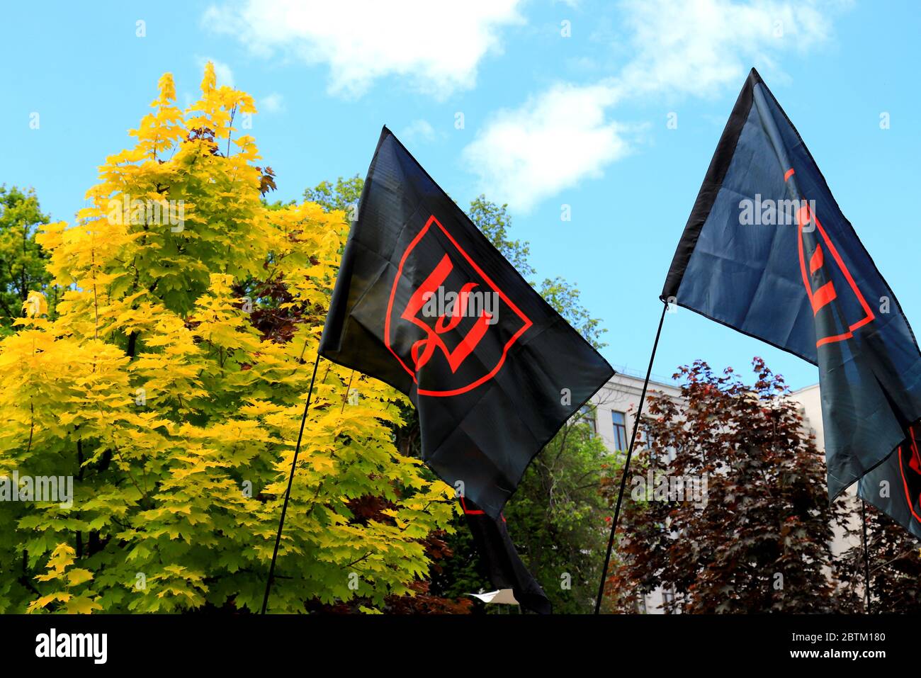 Una bandiera rossa nera patriottica Ucraina con uno stemma rosso dell'Ucraina vola durante una dimostrazione. Simbolo nazionale, bandiera di resistenza. Indipendenza Foto Stock