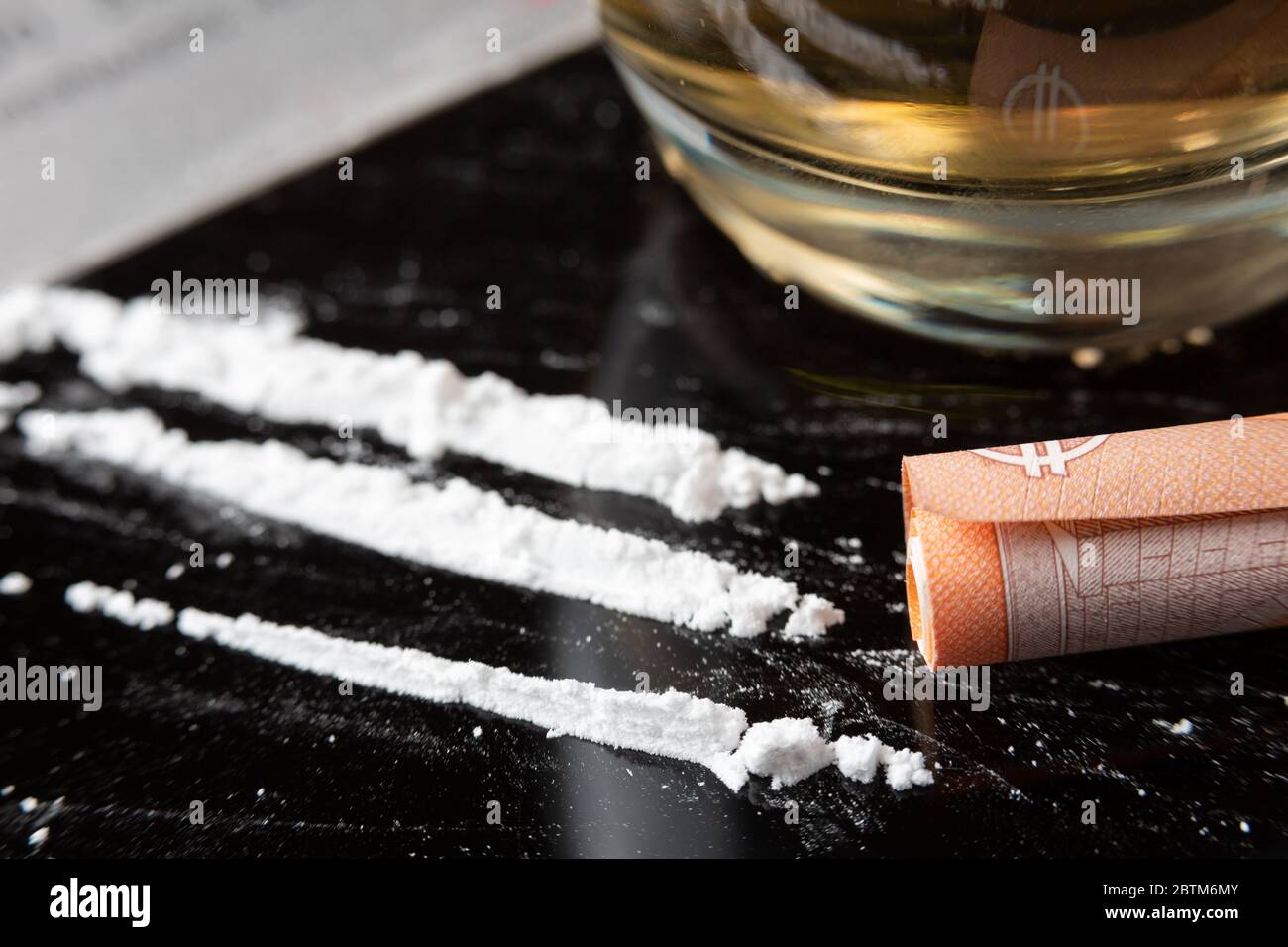 Linee di cocaina preparate su un tavolo e una banconota arrotolata pronta per essere sniffata Foto Stock