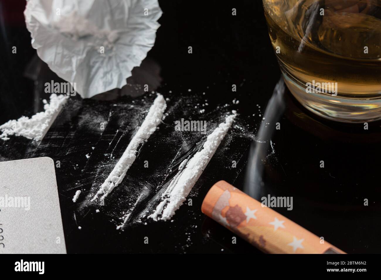 Linee di cocaina preparate su un tavolo e una banconota arrotolata pronta per essere sniffata Foto Stock