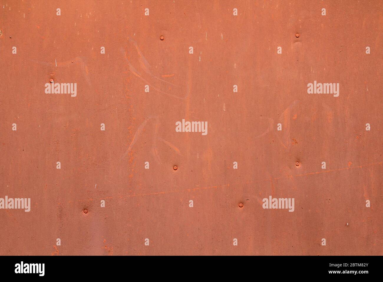 La parete è rossa arancione con graffi e graffi. Lamiera di ferro verniciata inchiodata. Lo sfondo per il testo e il design. Immagine per lo sfondo e lo sfondo. Foto Stock