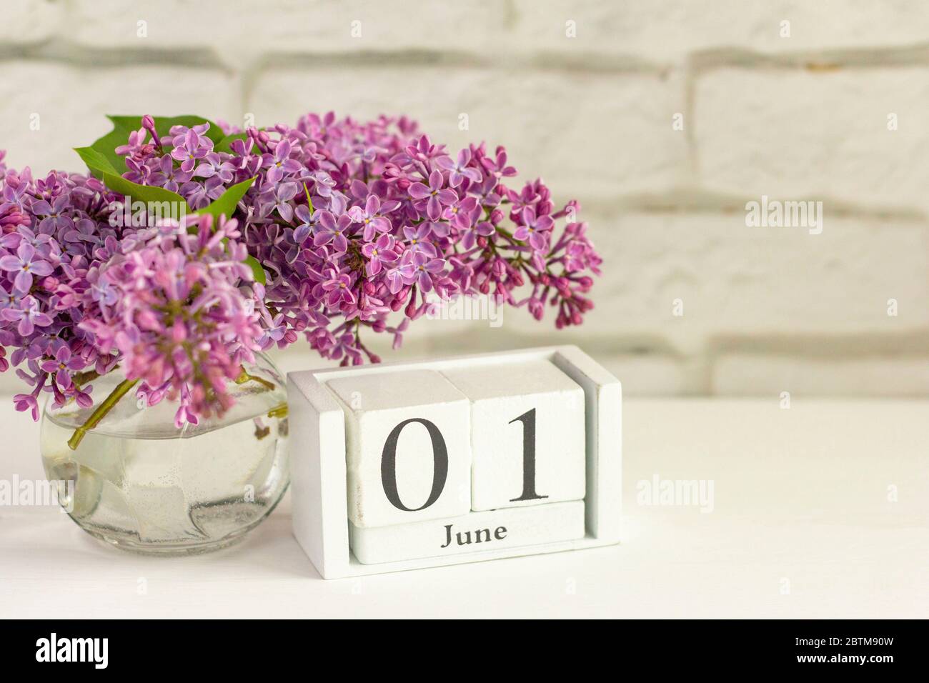 1 giugno su un calendario di legno accanto ai fiori. Il primo giorno d'estate. Giorno dei bambini. Spazio per la copia. Foto Stock