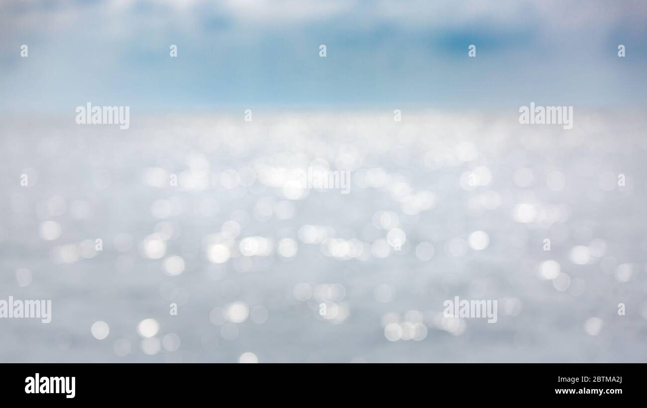 Sfondo di spiaggia offuscata tramonto e onde di mare con luci bokeh. Sfocatura artistica dell'oceano Foto Stock