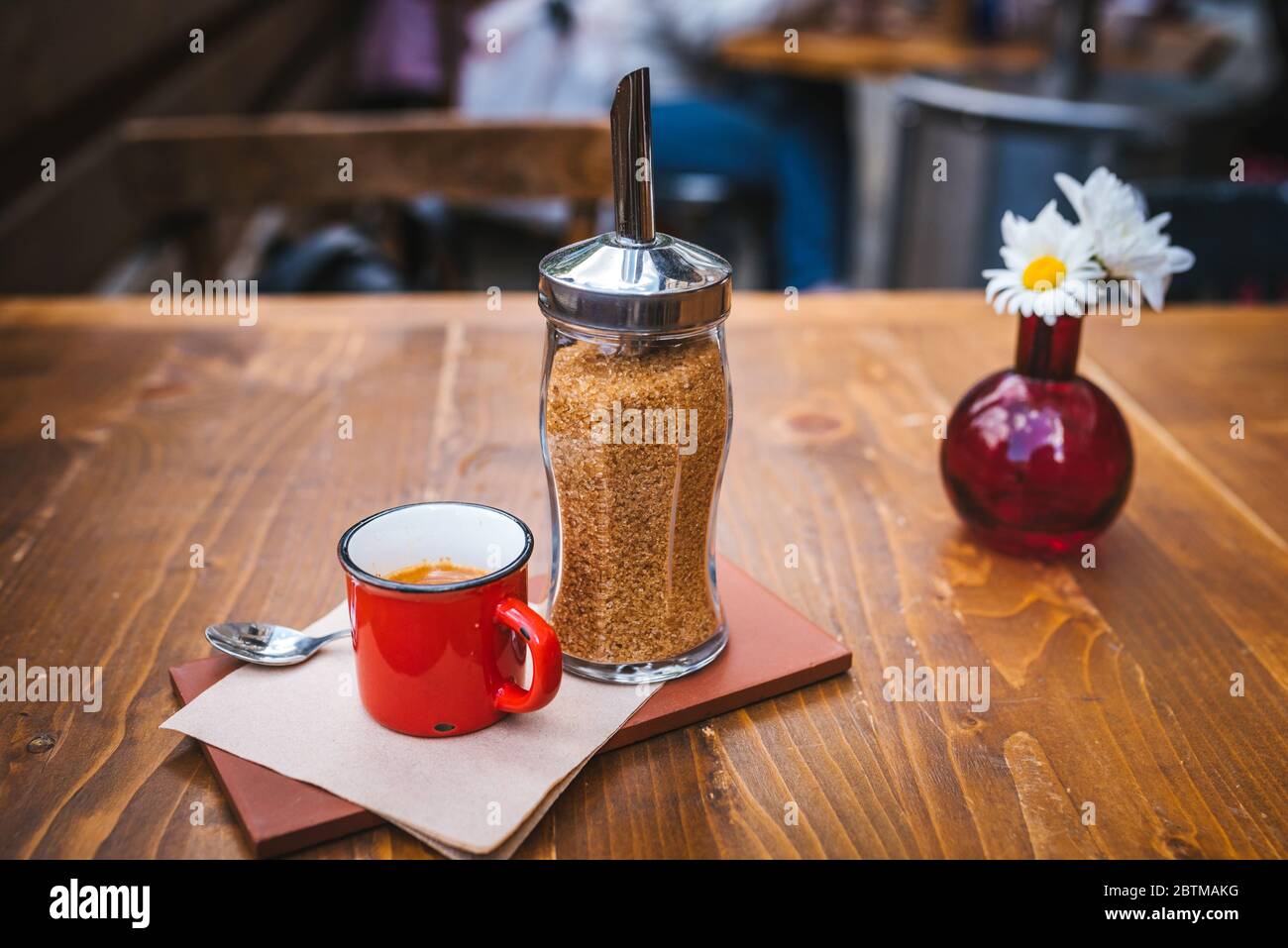 Tavolo da caffè all'aperto con un espresso in tazza sul tavolo e decorazione floreale sullo sfondo. Foto Stock