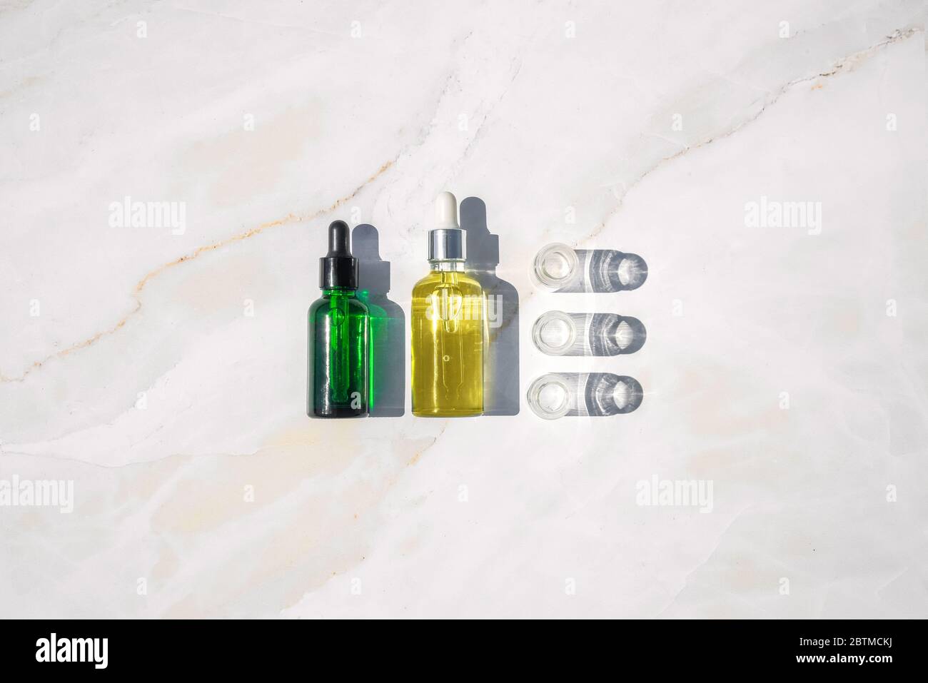 Olio omeopatico, siero e bottiglie con piante su fondo marmoreo Foto Stock