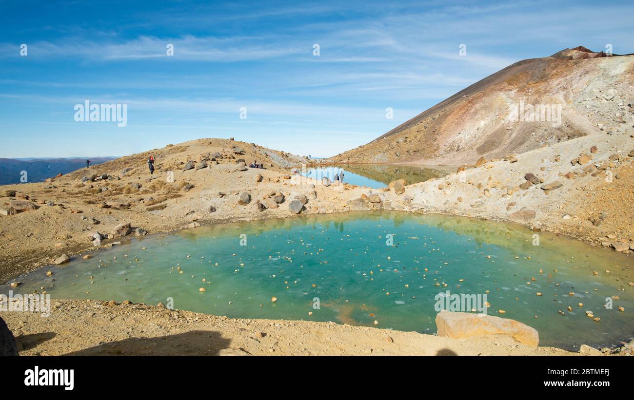 Laghi Smeraldo congelati con rocce sul ghiaccio gettate dai turisti, sul valico alpino di Tongariro in Nuova Zelanda Foto Stock