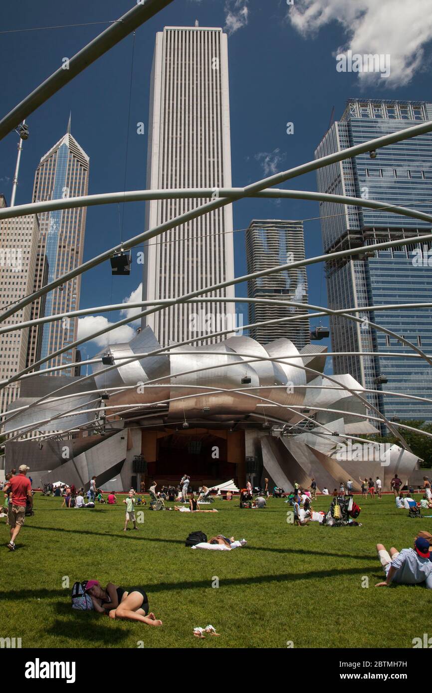 Alcune persone si trovano sull'erba del prato dell'auditorium Frank Gehry (Pritzker Pavilion), con lo skyline di Chicago come sfondo, Millenium Park Foto Stock