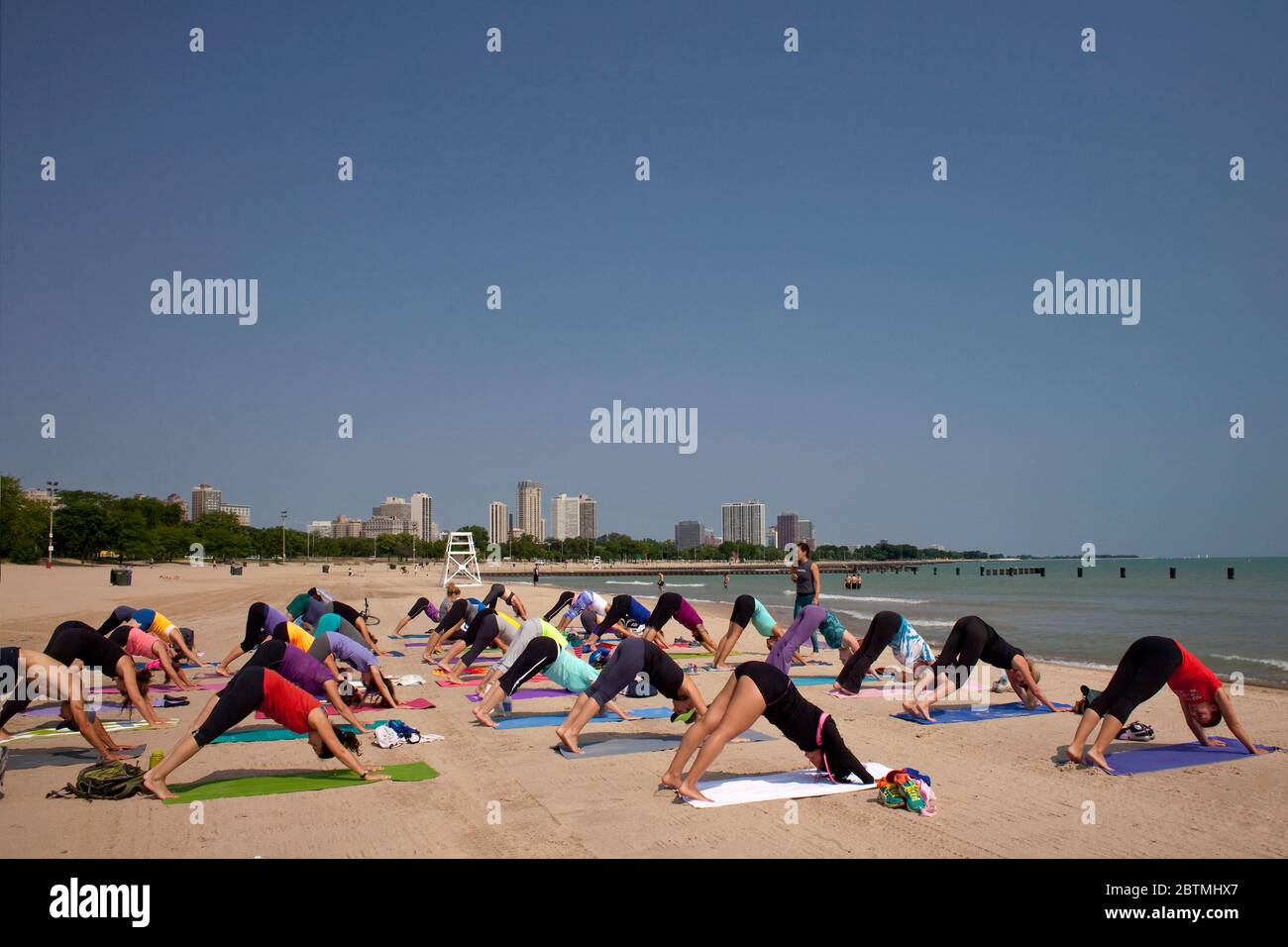 Scatto orizzontale di un gruppo di persone che praticano la ginnastica in una giornata estiva soleggiata, North Ave Beach, Chicago, Illinois, USA Foto Stock