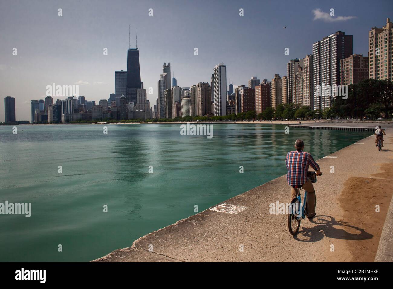 Vista orizzontale di due persone in bicicletta sul lago Michigan, con lo skyline di Chicago sullo sfondo, North Ave Beach, Illinois, USA Foto Stock
