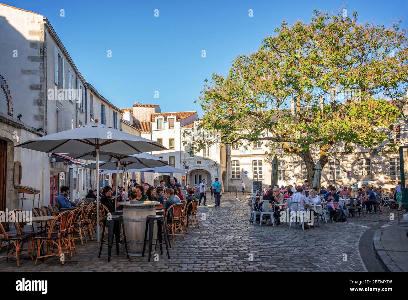 I turisti che mangiano all'aperto nei ristoranti all'aperto in estate in una pittoresca piazza della città vecchia di la Rochelle, Francia Foto Stock