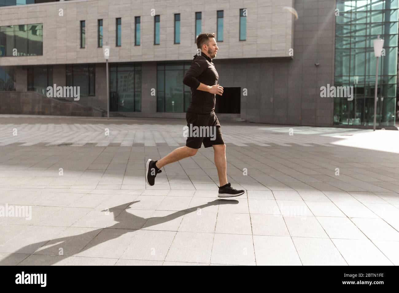 Giovane ragazzo sportivo che corre in centro città al mattino Foto Stock