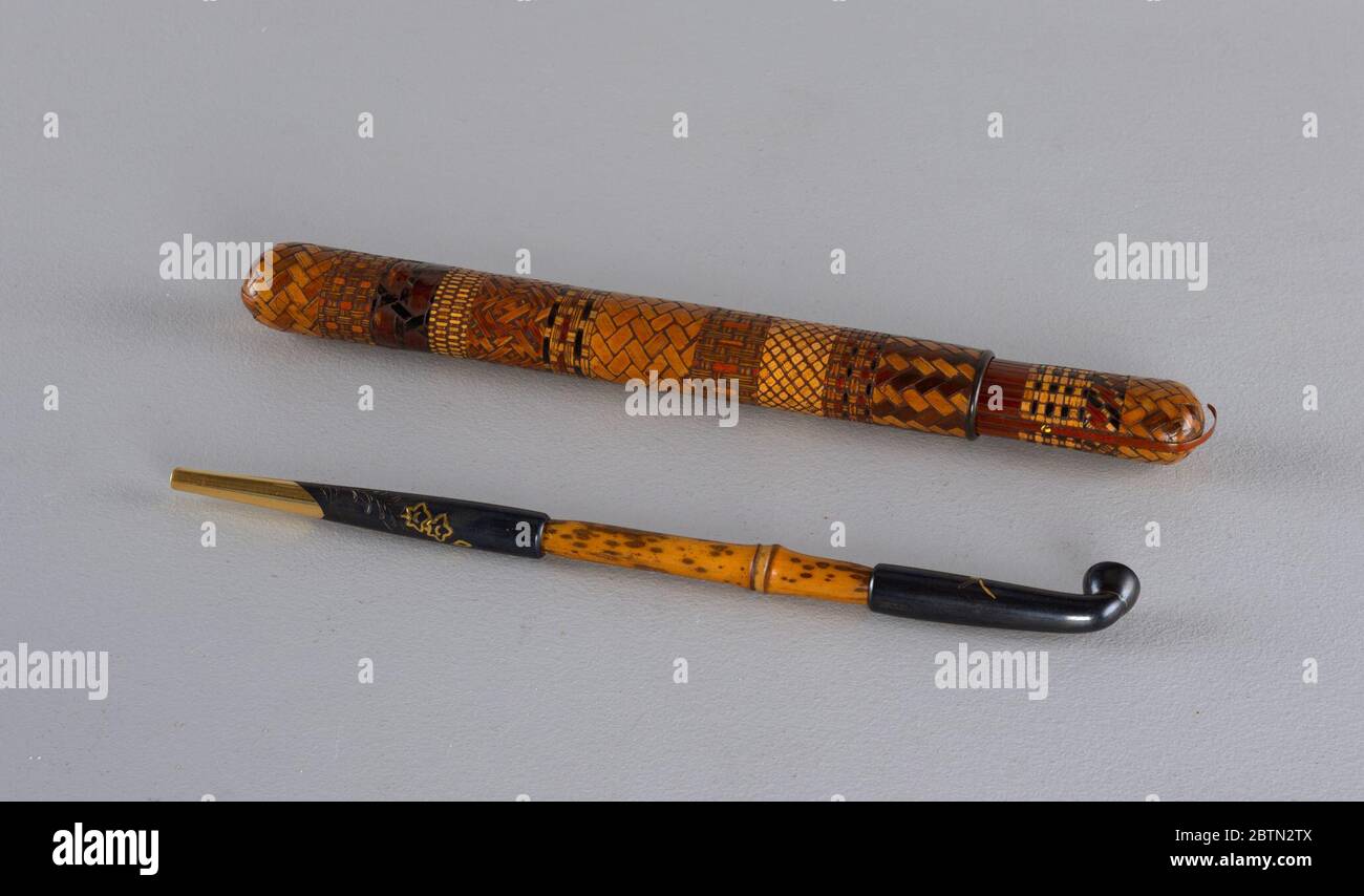 Tubo in oppio con custodia. Tubo (-16a) comprendente gambo di bambù con boccaglio e testa di metallo annerito e parzialmente dorato. Lungo ovale in due parti (-16b,c) di bambù alettato, sezioni scolpite e colorate in tre diversi modelli che simulano la tessitura del cesto; anello e bordo in metallo. Foto Stock