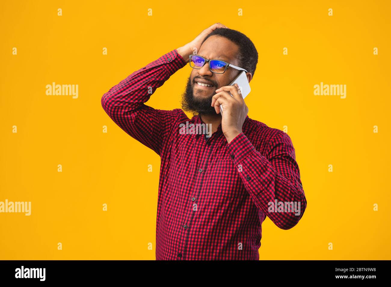Stressato nero ragazzo che parla al telefono e gesturing Foto Stock