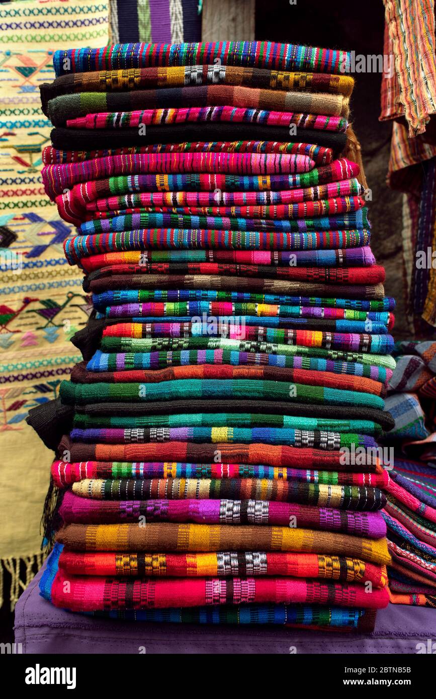 Una pila di tessuti guatemaltechi colorati e tessuti a mano si è accumulata su una bancarella del mercato. Santa Catarina, Lago Atitlán, Guatemala Foto Stock