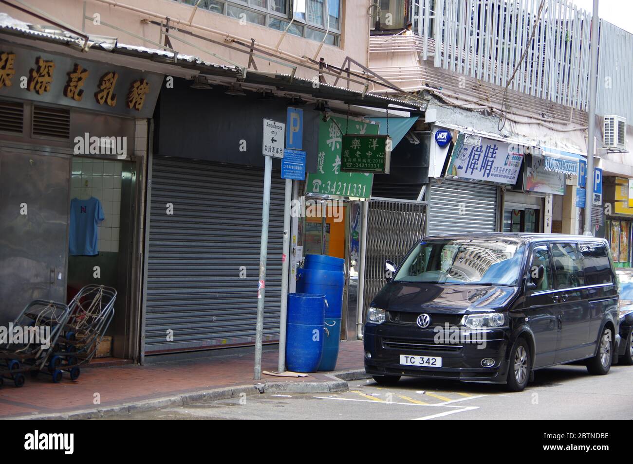 Hong Kong, Cina - 27 novembre 2016: Parcheggio nero Volkswagen Transporter sulla strada a Hongkong con bidoni blu in plastica sul marciapiede Foto Stock